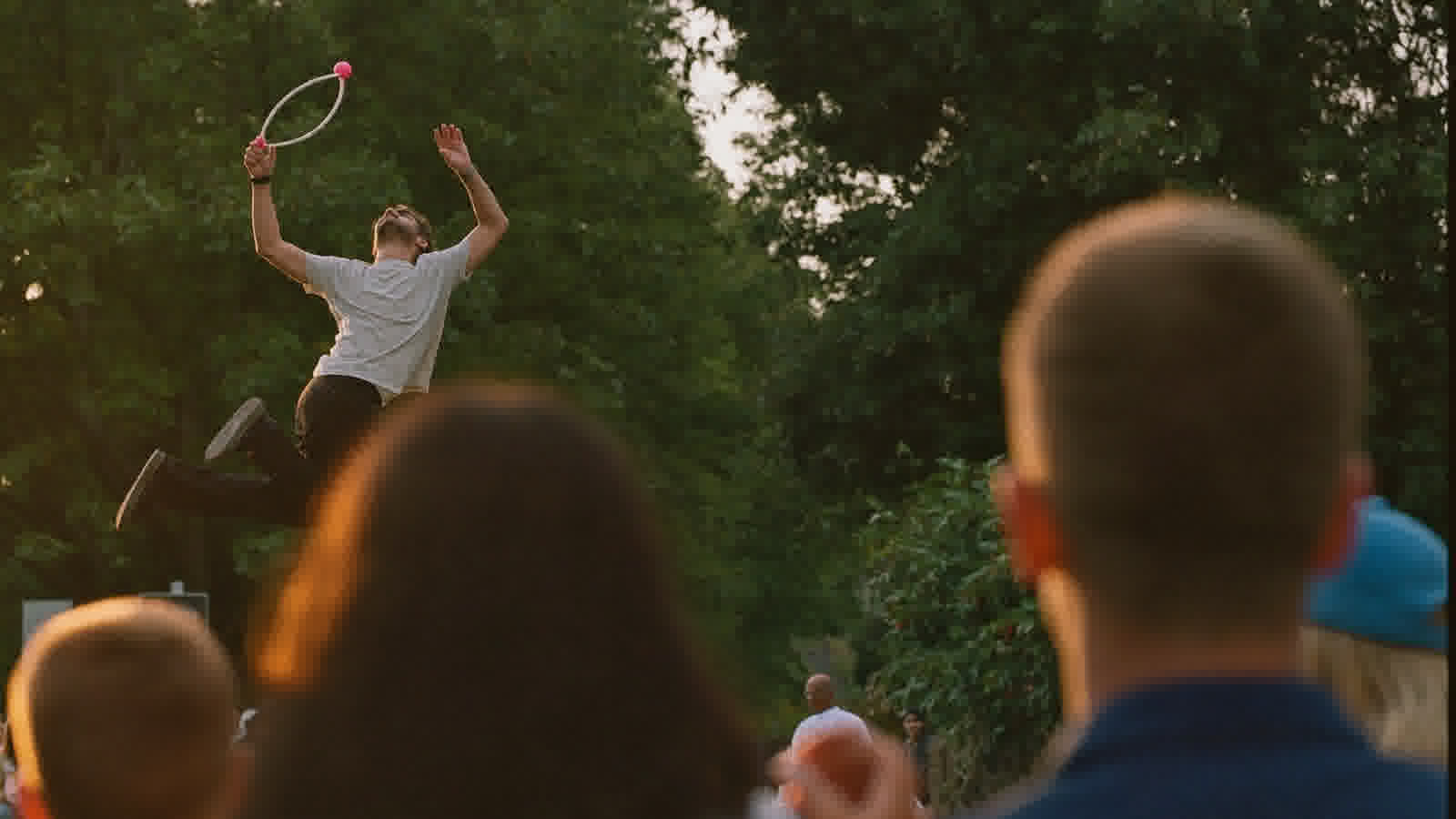 Illustration of a street performer spinning a hoop before a park crowd at golden hour