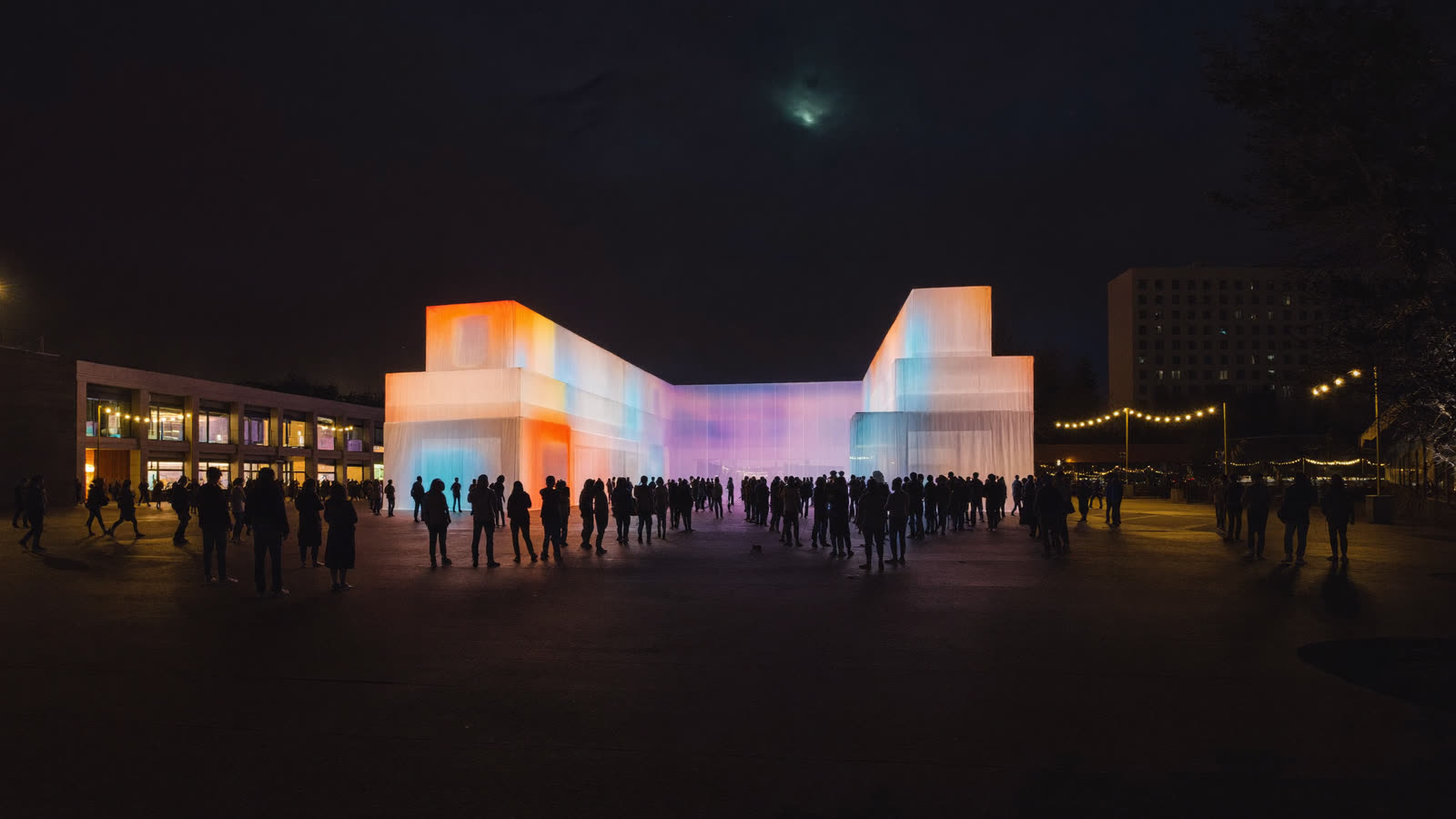 Light-art installation glowing over a crowd in a civic square at night