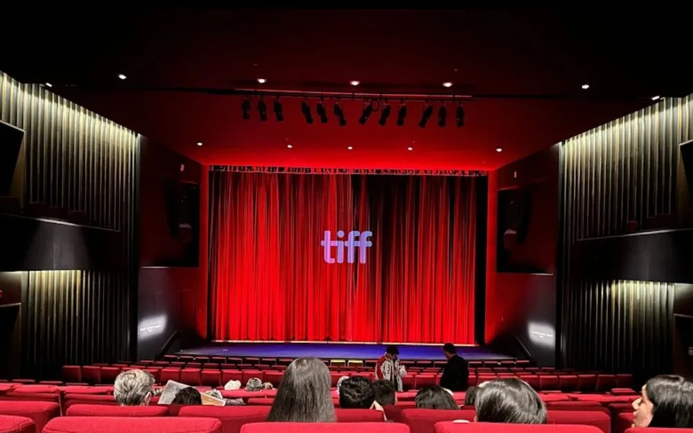 Red-seated cinema at TIFF Lightbox with the tiff logo projected on the curtain before a screening