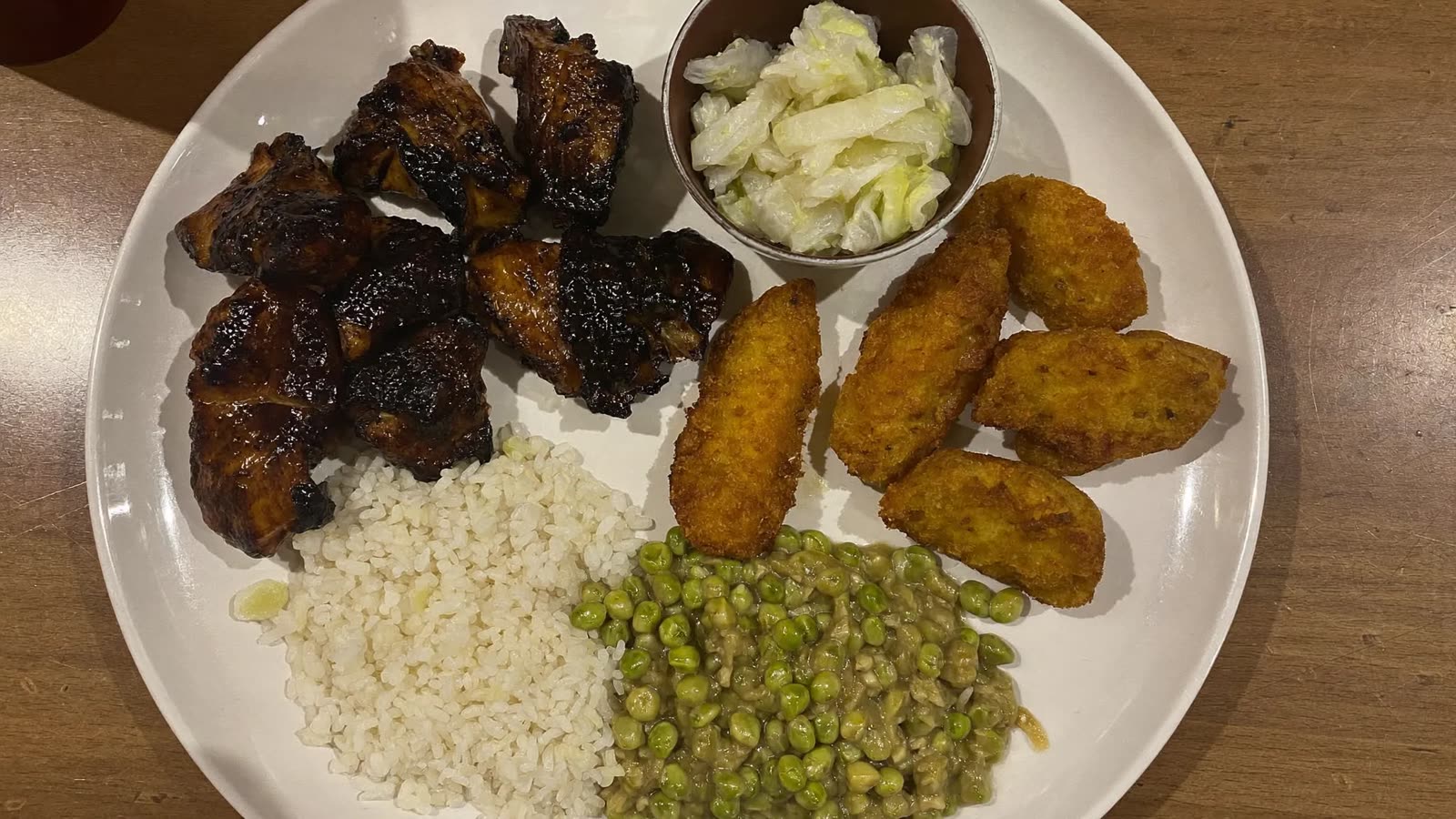 Jerk chicken, rice and peas, fried plantain and festival on a plate